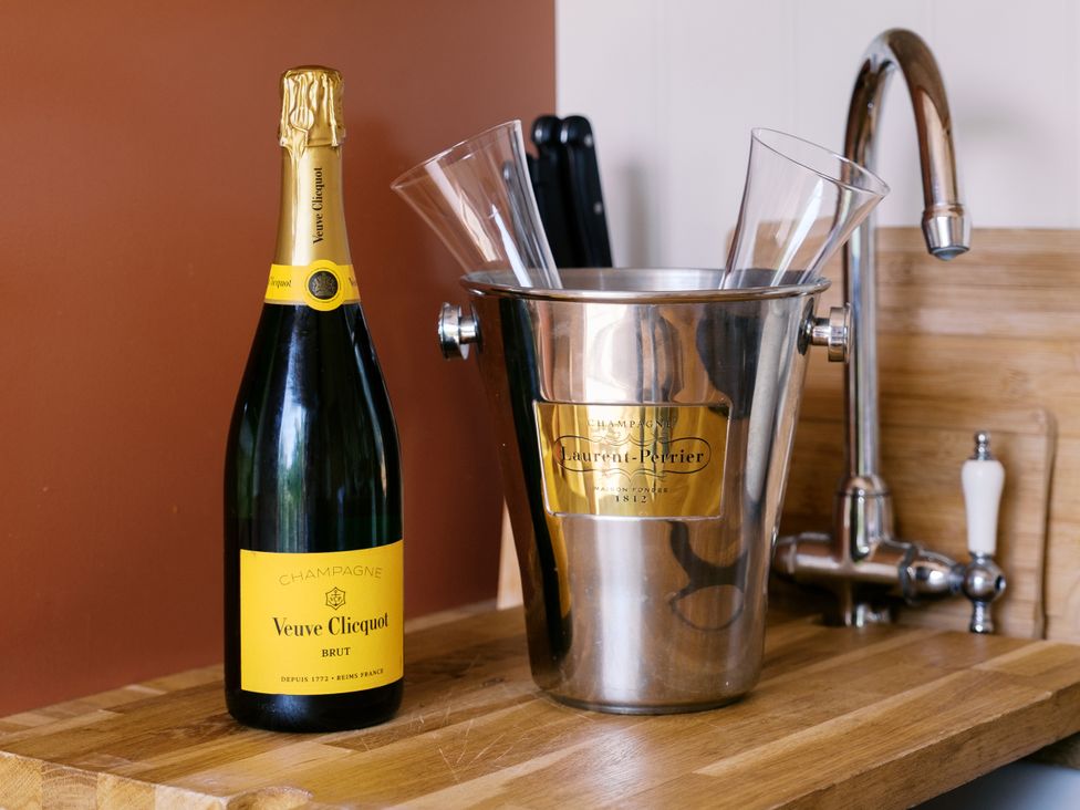 A kitchen countertop with champagne, glasses, and an ice bucket at Bonnie's Shepherds Hut at Shepherds Lodge Retreat and Wellness, Bottesford near Redmile and Vale of Belvoir