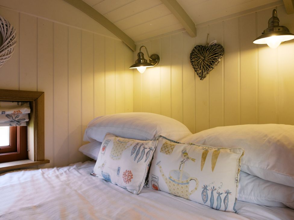 A bedroom with a bed and pillows at Bonnie's Shepherds Hut at Shepherds Lodge Retreat and Wellness in Bottesford near Redmile and Vale of Belvoir