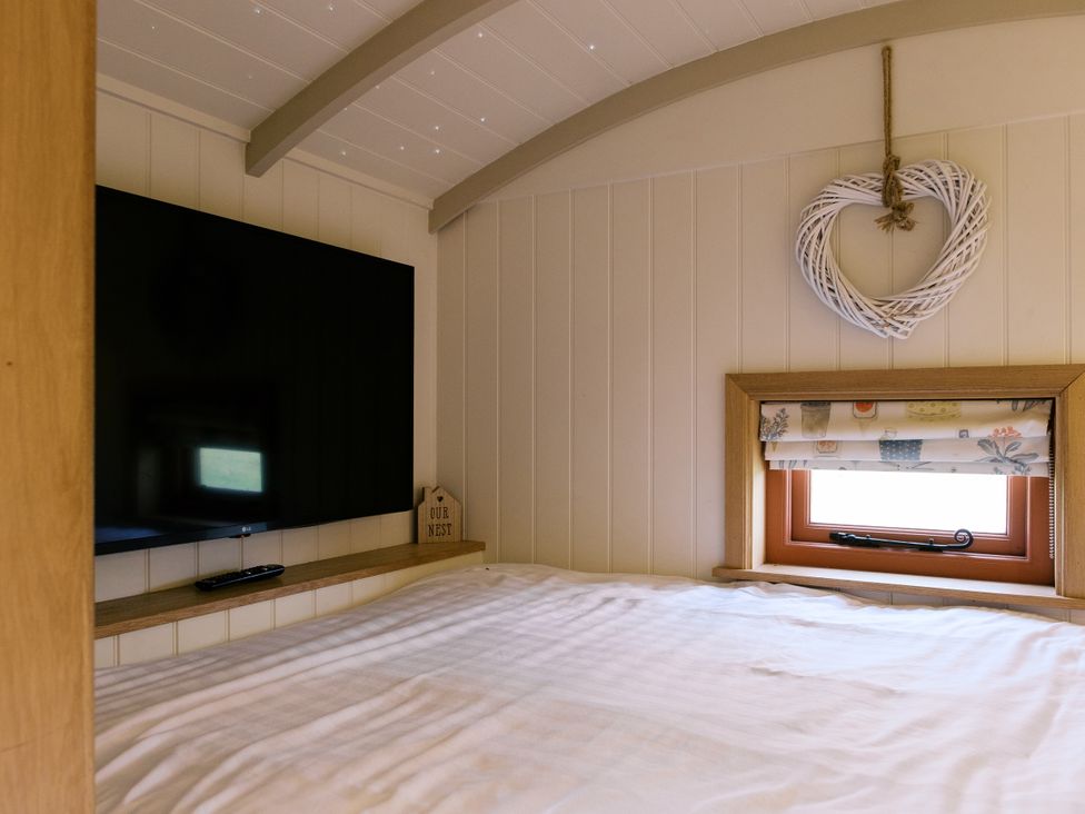 A bedroom with a television and window at Bonnie's Shepherds Hut at Shepherds Lodge Retreat and Wellness Bottesford near Redmile and Vale of Belvoir