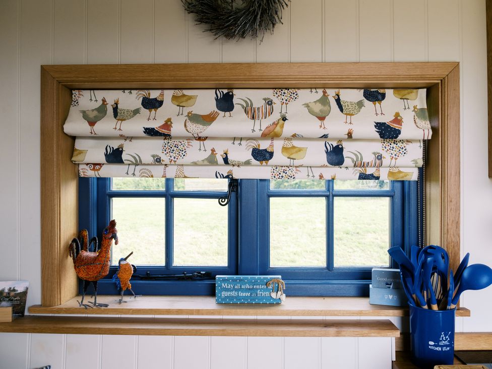 A kitchen window with decorative roller blind and bird figurines at Lillie's Shepherds Hut at Shepherds Lodge Retreat and Wellness Bottesford near Redmile and Vale of Belvoir