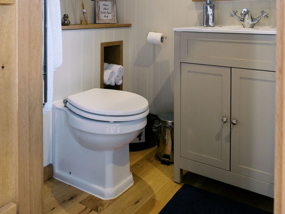 A bathroom featuring a toilet, sink and cabinet at Lillie's Shepherds Hut at Shepherds Lodge Retreat and Wellness Bottesford near Redmile and Vale of Belvoir