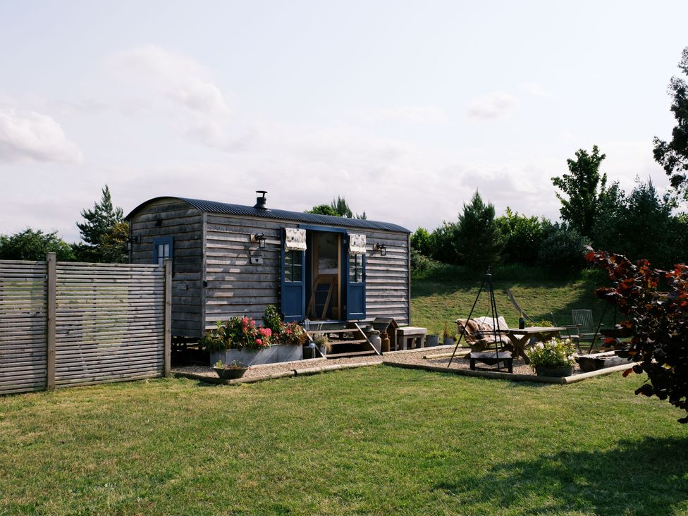 A hut with an outdoor seating area at Lillie's Shepherds Hut at Shepherds Lodge Retreat and Wellness Bottesford near Redmile and Vale of Belvoir