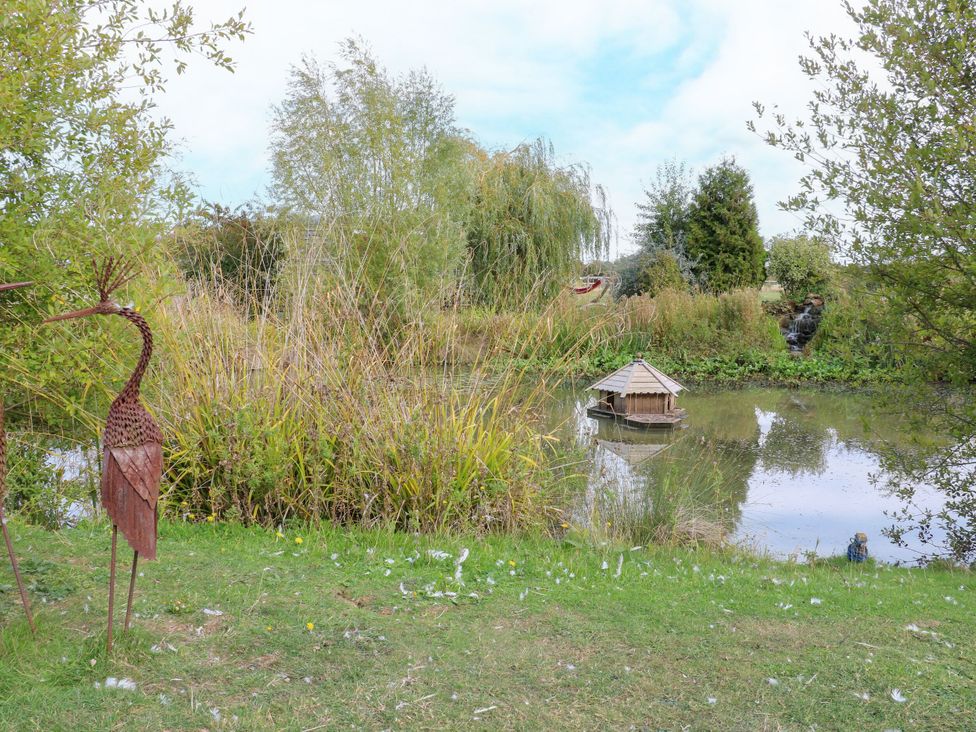 A pond with a decorative house and metal sculpture at Lillie's Shepherds Hut at Shepherds Lodge Retreat and Wellness Bottesford near Redmile and Vale of Belvoir