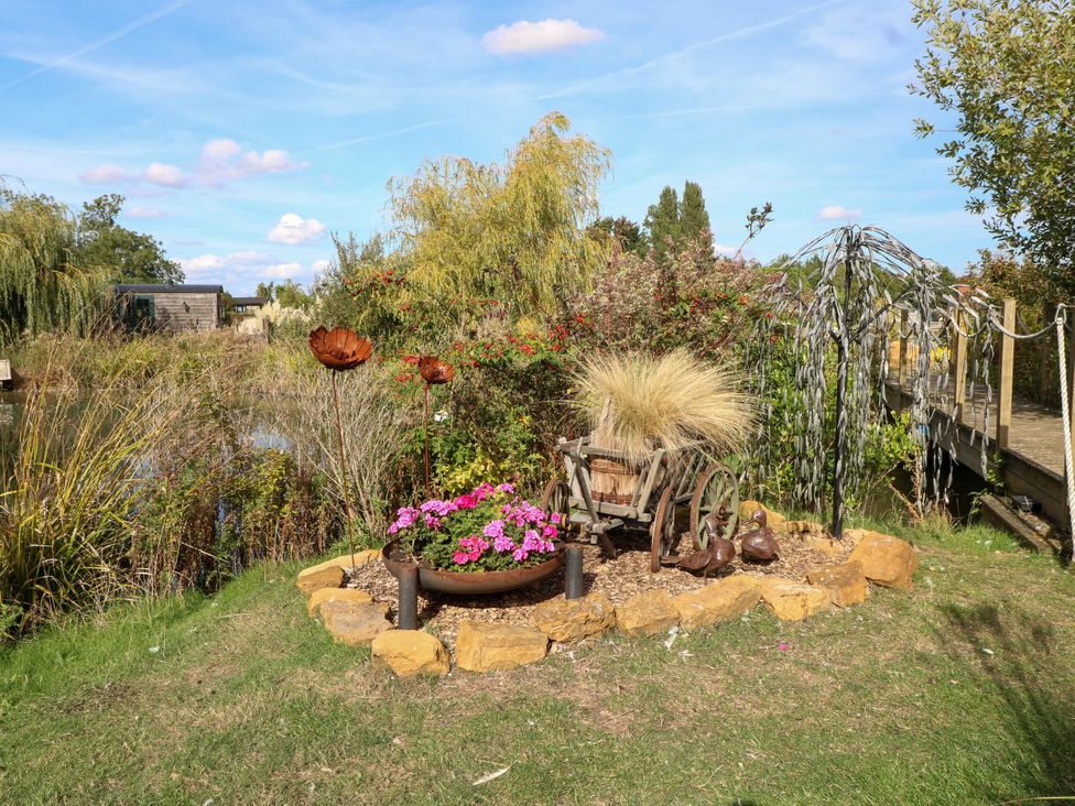 A garden with flowers in a wheelbarrow and metal sculptures at Lillie's Shepherds Hut at Shepherds Lodge Retreat and Wellness Bottesford near Redmile and Vale of Belvoir