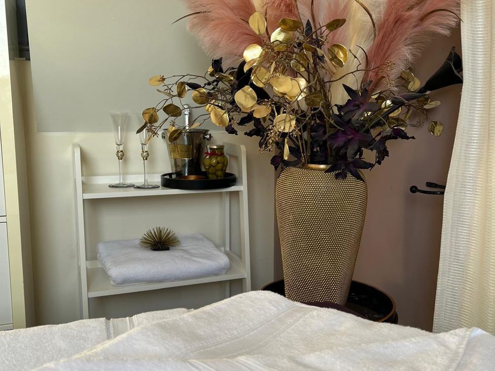 A flower arrangement with a vase and glasses on shelves at Lillie's Shepherds Hut at Shepherds Lodge Retreat and Wellness near Bottesford