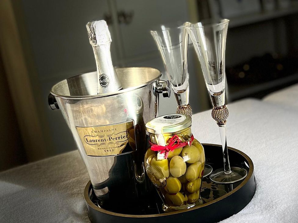 A champagne bottle, glasses, and olives on a tray at Lillie's Shepherds Hut at Shepherds Lodge Retreat and Wellness Bottesford near Redmile and Vale of Belvoir