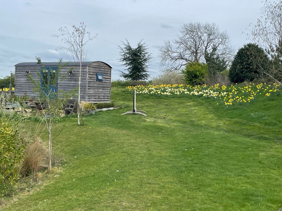 A shepherd hut in a garden with flowers at Lillie's Shepherds Hut at Shepherds Lodge Retreat and Wellness Bottesford near Redmile and Vale of Belvoir