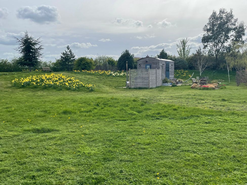 A garden with a hut and flowers at Lillie's Shepherds Hut at Shepherds Lodge Retreat and Wellness near Bottesford