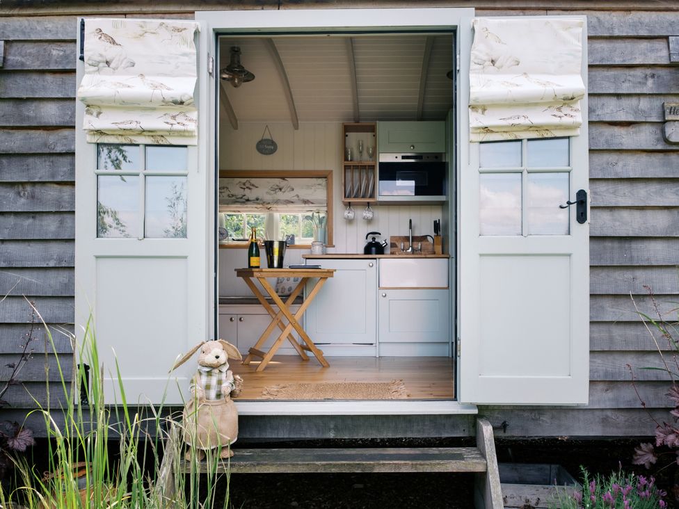 A kitchen with a table and chairs visible at Herbie's Shepherds Hut at Shepherds Lodge Retreat and Wellness Bottesford near Redmile and Vale of Belvoir