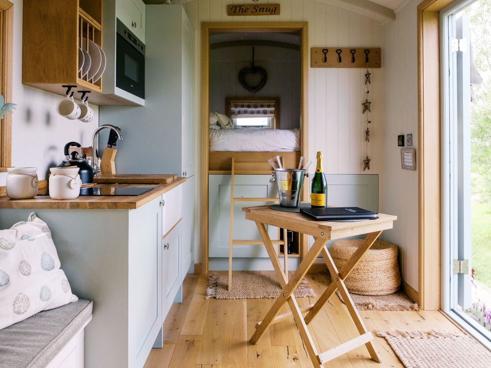A snug with kitchen area and dining table at Herbie's Shepherds Hut at Shepherds Lodge Retreat and Wellness Bottesford near Redmile and Vale of Belvoir