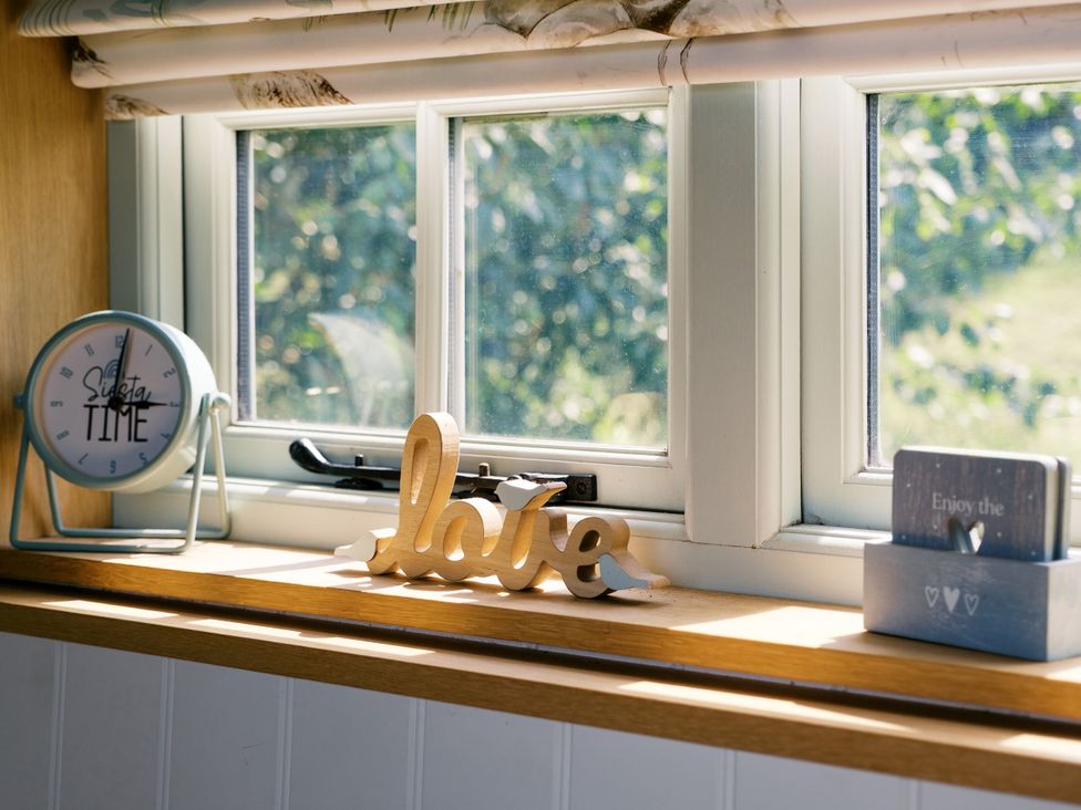 A kitchen window with a clock and wooden decorations at Herbie's Shepherds Hut at Shepherds Lodge Retreat and Wellness Bottesford near Redmile and Vale of Belvoir