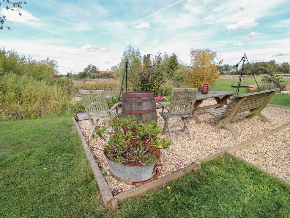 A garden seating area with a table and chairs at Herbie's Shepherds Hut at Shepherds Lodge Retreat and Wellness Bottesford near Redmile and Vale of Belvoir