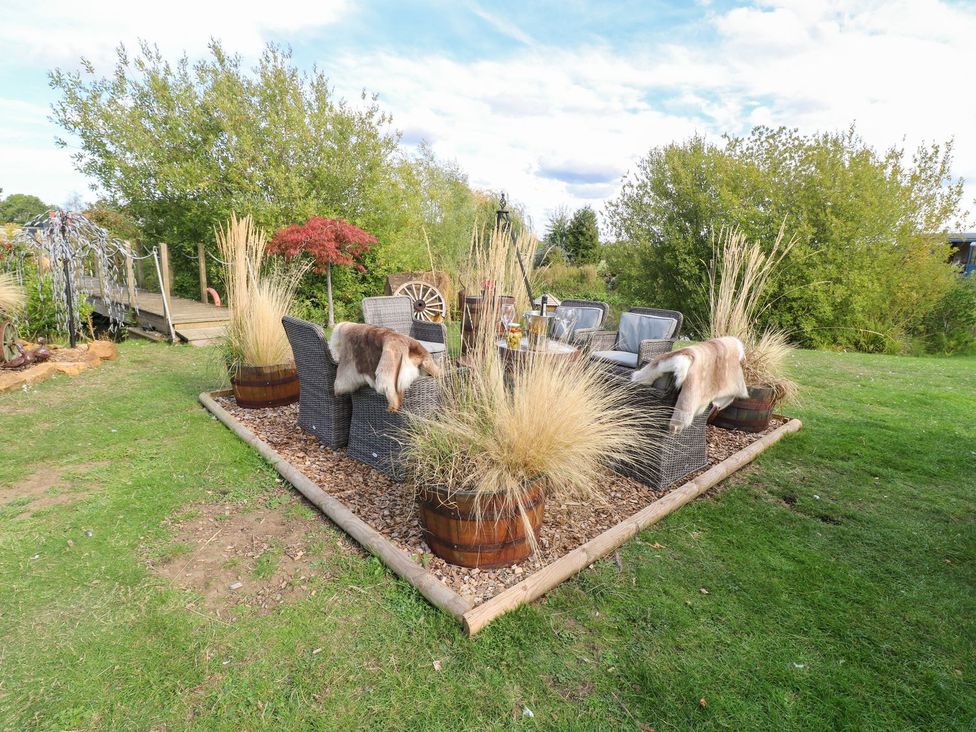 An outdoor seating area with chairs and a table at Herbie's Shepherds Hut at Shepherds Lodge Retreat and Wellness Bottesford near Redmile and Vale of Belvoir