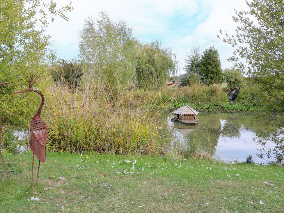 A garden with a pond and a metal sculpture at Herbie's Shepherds Hut at Shepherds Lodge Retreat and Wellness Bottesford near Redmile and Vale of Belvoir