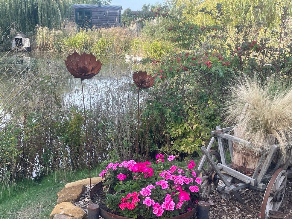 A garden with flowers and decorative metal art at Herbie's Shepherds Hut at Shepherds Lodge Retreat and Wellness, Bottesford near Redmile and Vale of Belvoir
