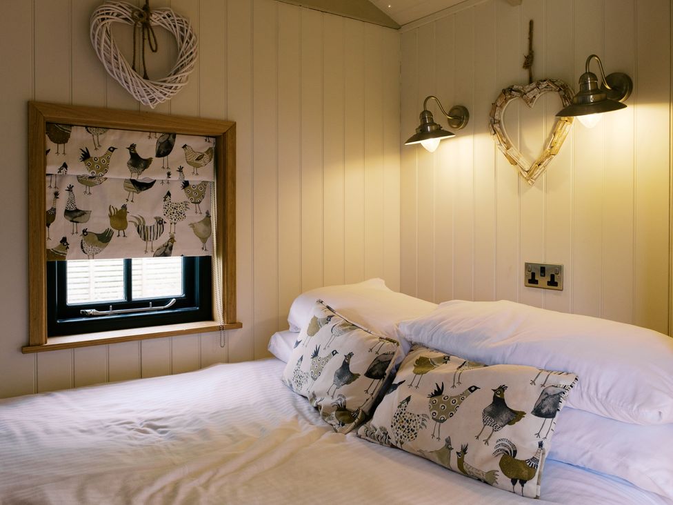 A bedroom with a bed and pillows at Poppie's Shepherds Hut at Shepherds Lodge Retreat and Wellness Bottesford near Redmile and Vale of Belvoir