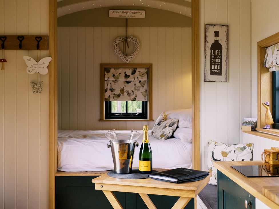 A sleeping area with champagne and an ice bucket at Poppie's Shepherds Hut at Shepherds Lodge Retreat and Wellness in Bottesford near Redmile and Vale of Belvoir