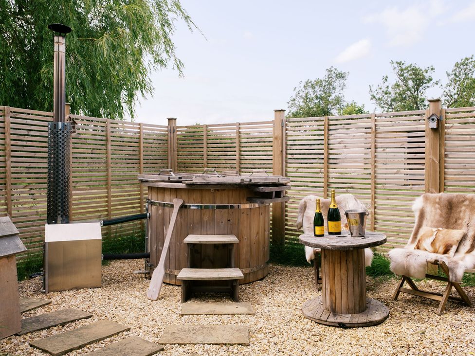 An outdoor area with a hot tub and furniture at Poppie's Shepherds Hut at Shepherds Lodge Retreat and Wellness Bottesford near Redmile and Vale of Belvoir