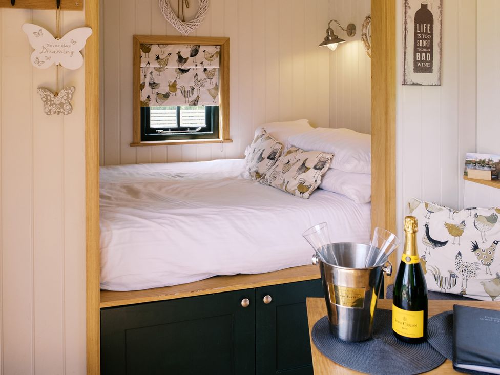 A bedroom with a bed and wine bottle at Poppie's Shepherds Hut at Shepherds Lodge Retreat and Wellness Bottesford near Redmile and Vale of Belvoir