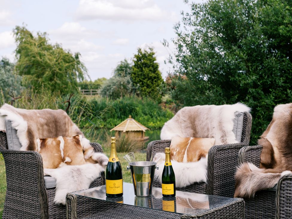 A garden with outdoor chairs and champagne bottles at Poppie's Shepherds Hut at Shepherds Lodge Retreat and Wellness, Bottesford near Redmile and Vale of Belvoir