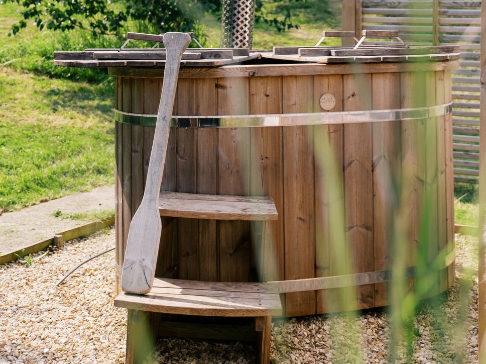 A hot tub with wooden steps and a paddle at Poppie's Shepherds Hut at Shepherds Lodge Retreat and Wellness in Bottesford near Redmile and Vale of Belvoir