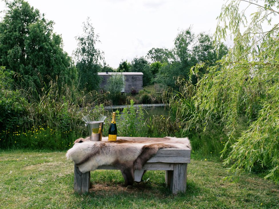 A table with a champagne bottle and ice bucket in a garden at Poppie's Shepherds Hut at Shepherds Lodge Retreat and Wellness Bottesford near Redmile and Vale of Belvoir