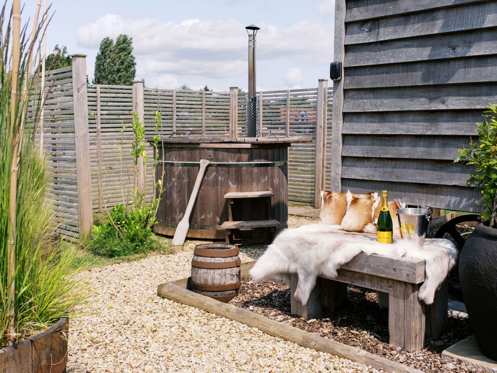 An outdoor area with a hot tub and wooden bench at Poppie's Shepherds Hut at Shepherds Lodge Retreat and Wellness, Bottesford near Redmile and Vale of Belvoir