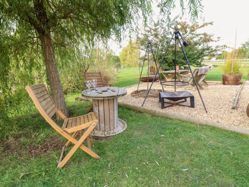 A garden with a table and chairs at Poppie's Shepherds Hut at Shepherds Lodge Retreat and Wellness Bottesford near Redmile and Vale of Belvoir