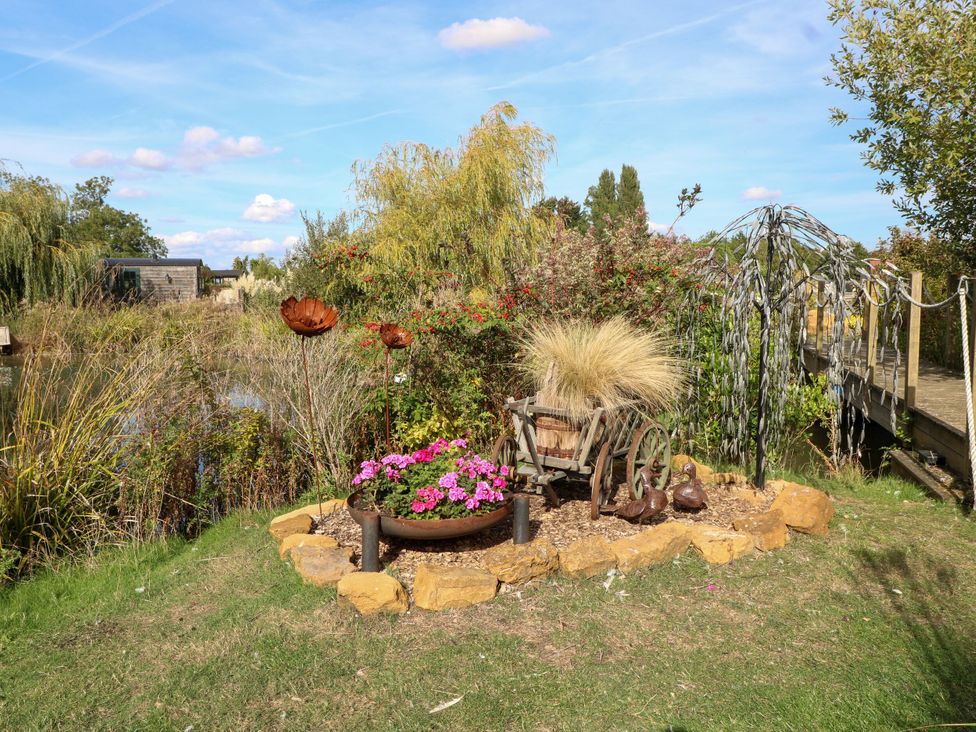 A garden area with flowers, a bicycle, and sculptures at Poppie's Shepherds Hut at Shepherds Lodge Retreat and Wellness Bottesford near Redmile and Vale of Belvoir