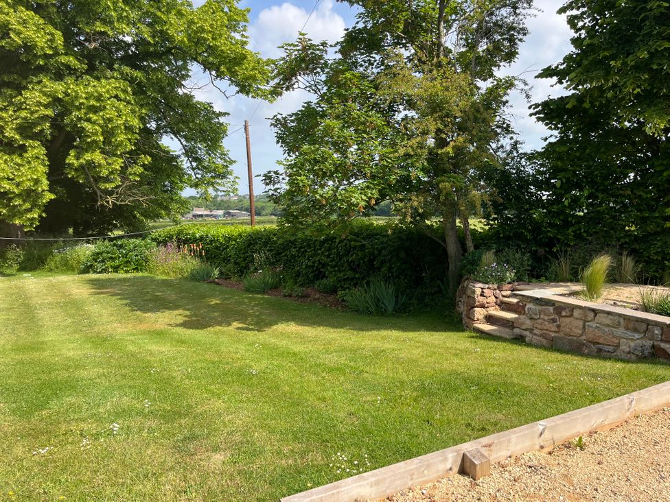 A garden with grass lawn trees flowerbed and stone steps at The Gables in Spaxton near Nether Stowey