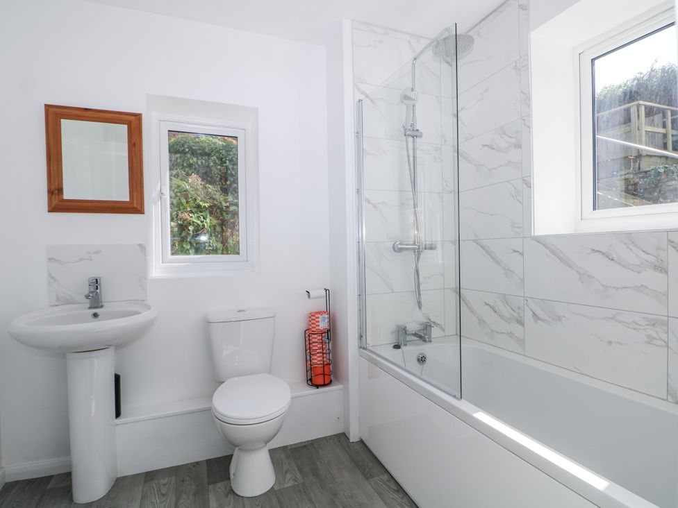 A bathroom with a sink, toilet, shower, and window at 108 Emmanuel Road in Hastings