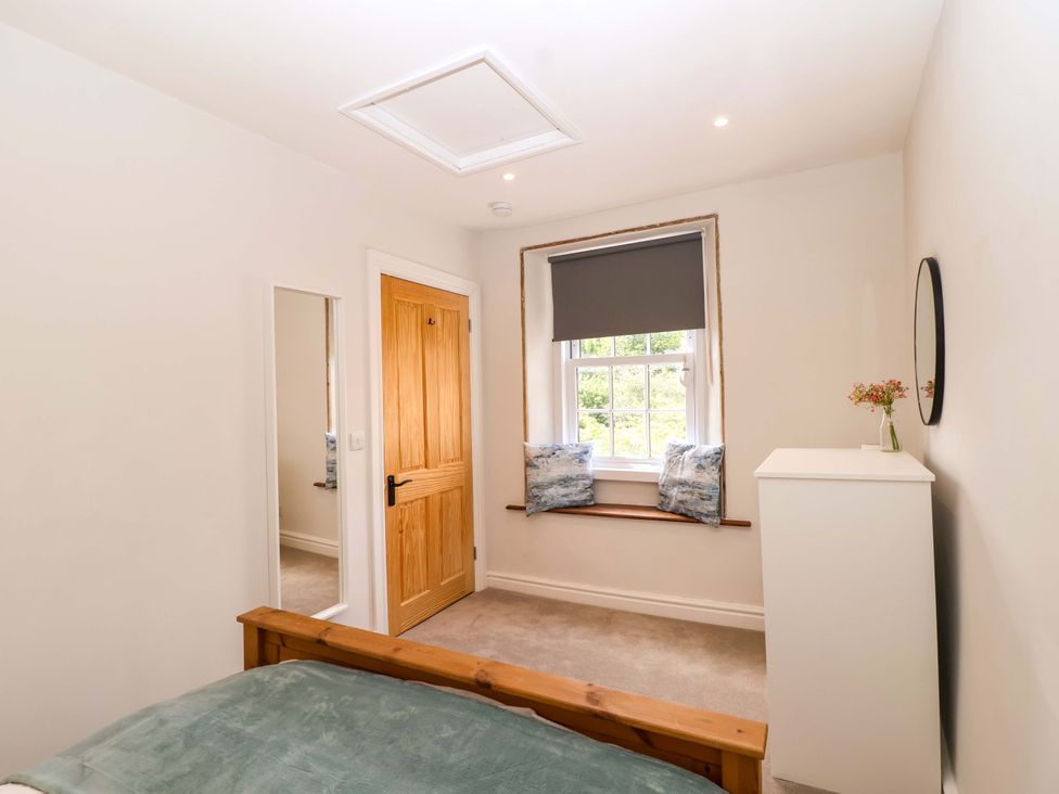 A bedroom with a bed, mirror, and window at Walnut Major in Kingsbridge