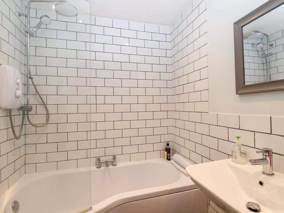 A bathroom with a bathtub, shower, sink and mirror at Walnut Major in Kingsbridge