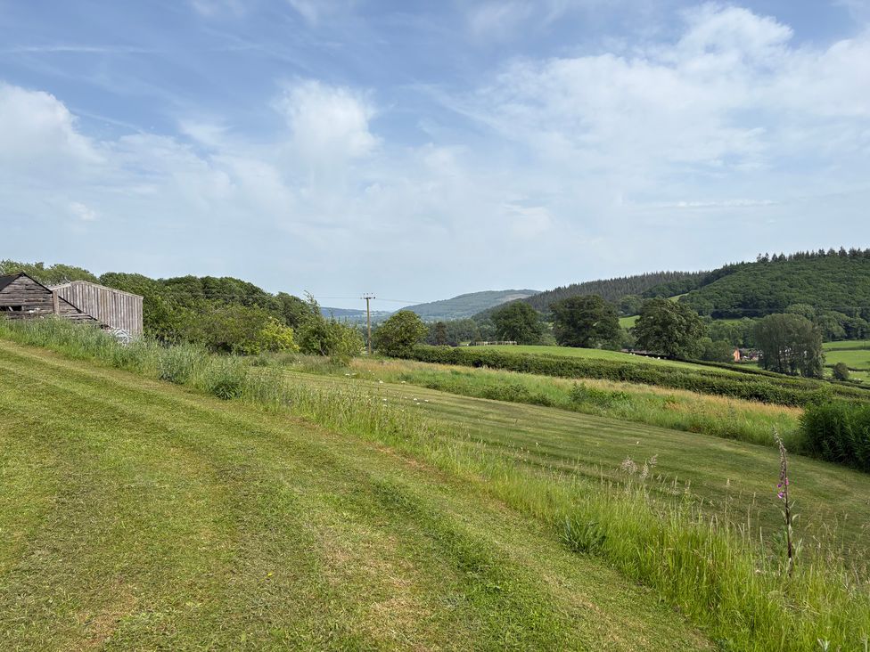 A view of grass and hills with a wooden building at Cottage 1 in Presteigne