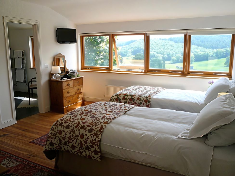 A bedroom with twin beds and a window overlooking hills at Cottage 1 Presteigne