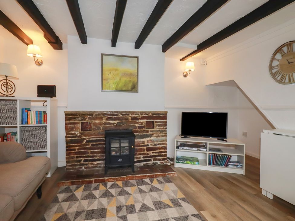 A living room with a fireplace, sofa, and television at Honeysuckle Cottage in Charlestown