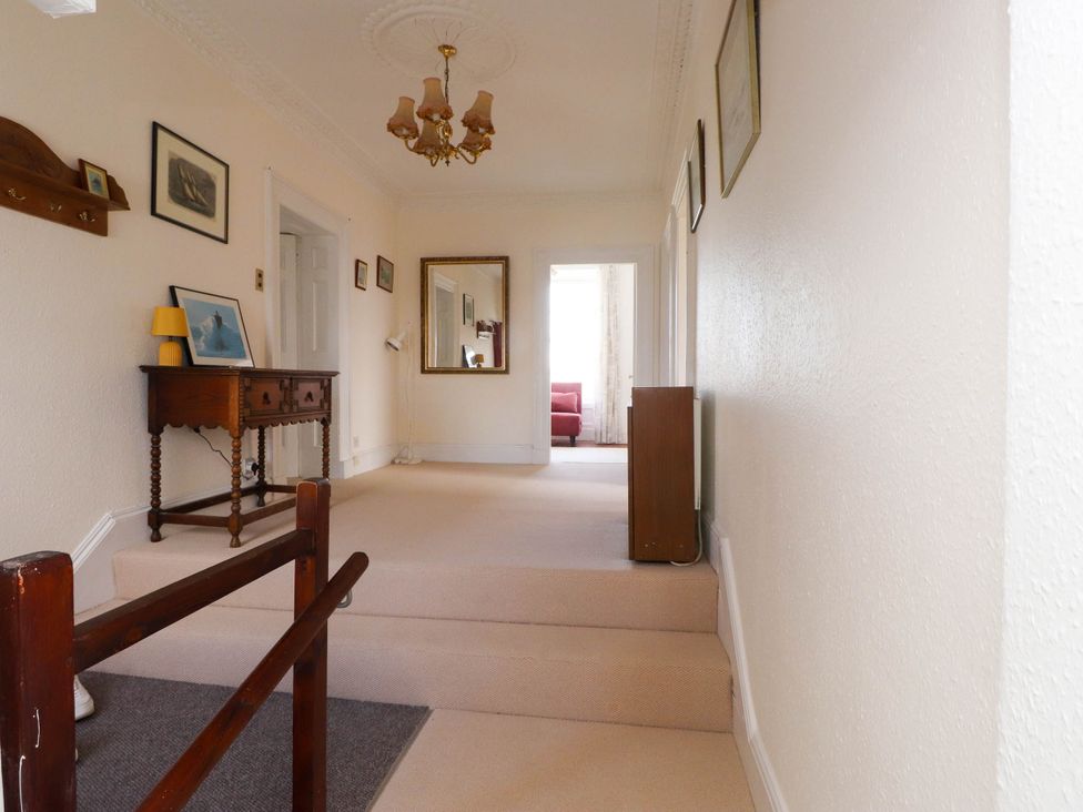 A hallway with a wooden console table and framed pictures on the walls at Flat 3 in Trearddur Bay