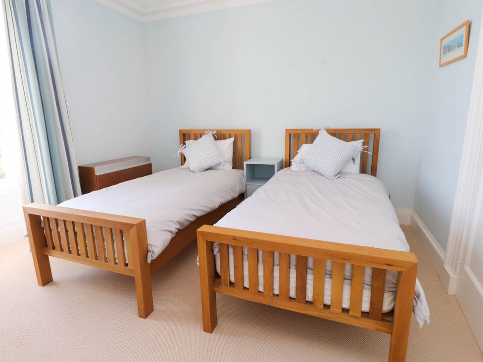 A bedroom with two wooden single beds and a small nightstand between them at Flat 3 in Trearddur Bay