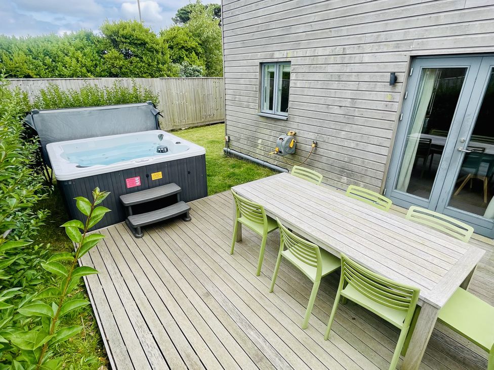 A garden with a hot tub and dining furniture at Una, Lodge 73 Carbis Bay