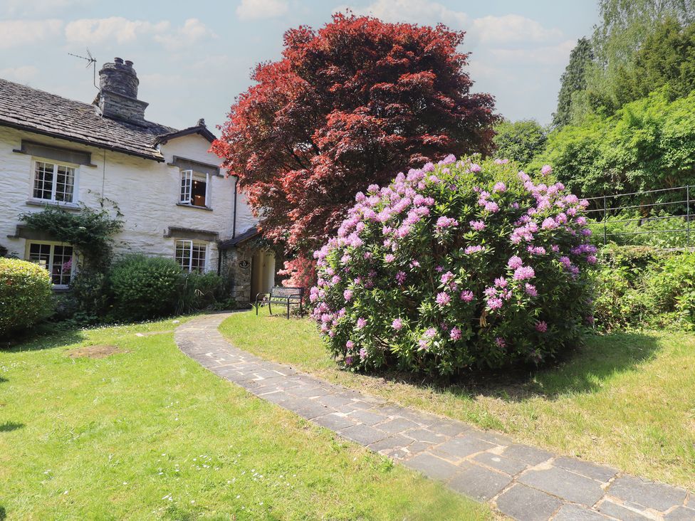 A garden with a house, bushes, flowers, and a pathway at Daffodils in Ambleside