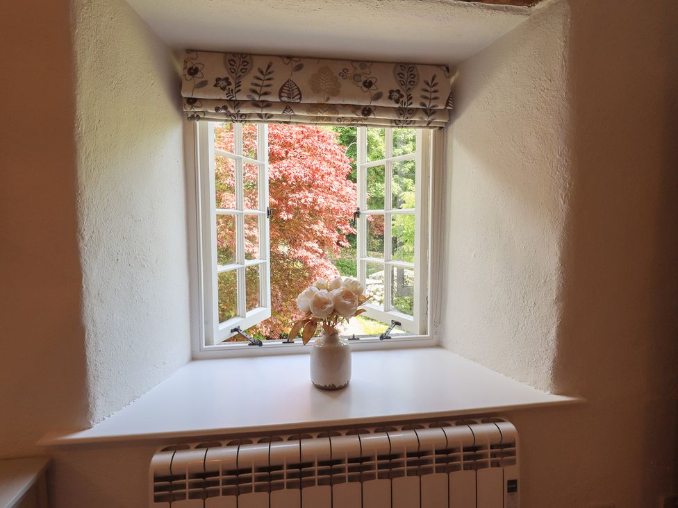 A window with a vase of flowers and a radiator at Daffodils in Ambleside
