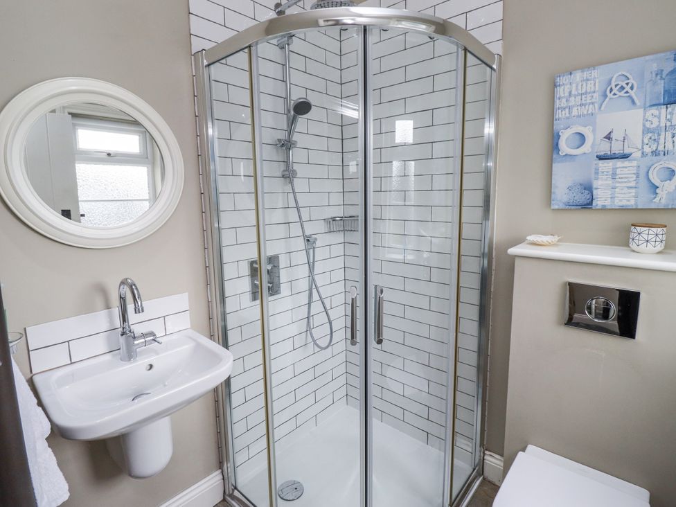 A bathroom with shower, sink, and mirror at Driftwood in 