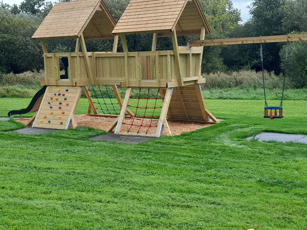A playground with a climbing structure and swings at Gooseberry Cottage in Lisnaskea