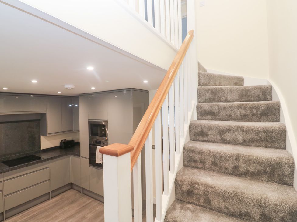 A staircase leading to upper level with kitchen in view at Boslowen Portreath