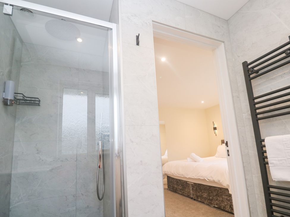 A bathroom with a shower and doorway to a bedroom at Boslowen Portreath