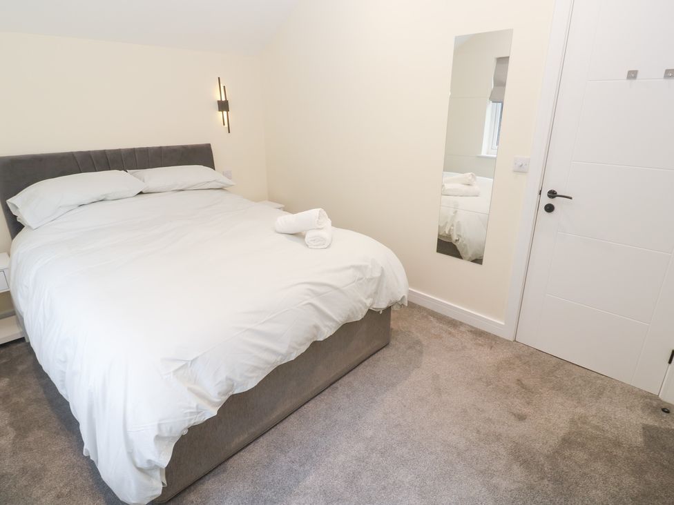 A bedroom with a bed and mirror at Boslowen in Portreath