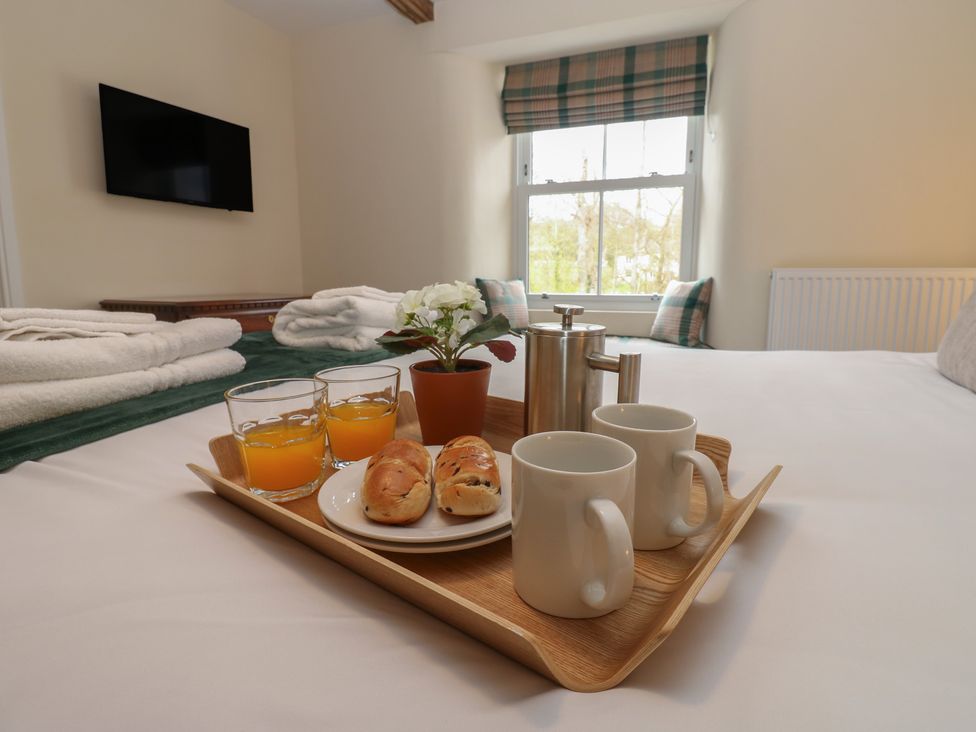 A bedroom with a breakfast tray containing drinks and pastries at 1 Brookside in Warcop