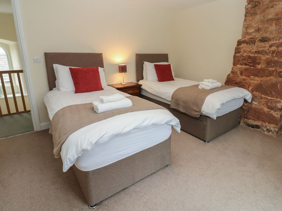 A bedroom with two single beds and a bedside table at 1 Brookside in Warcop