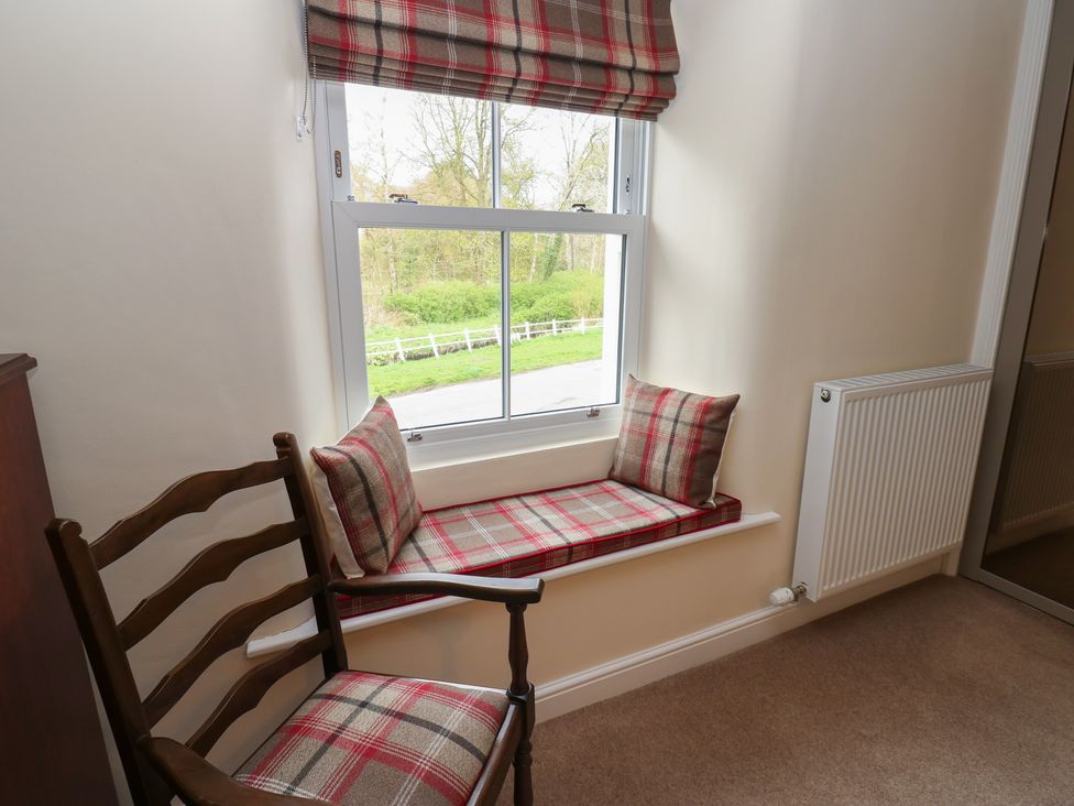 A sitting room with a window seat and chair at 1 Brookside in Warcop