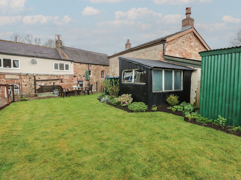 A garden with a table and chairs and a shed at 1 Brookside Warcop